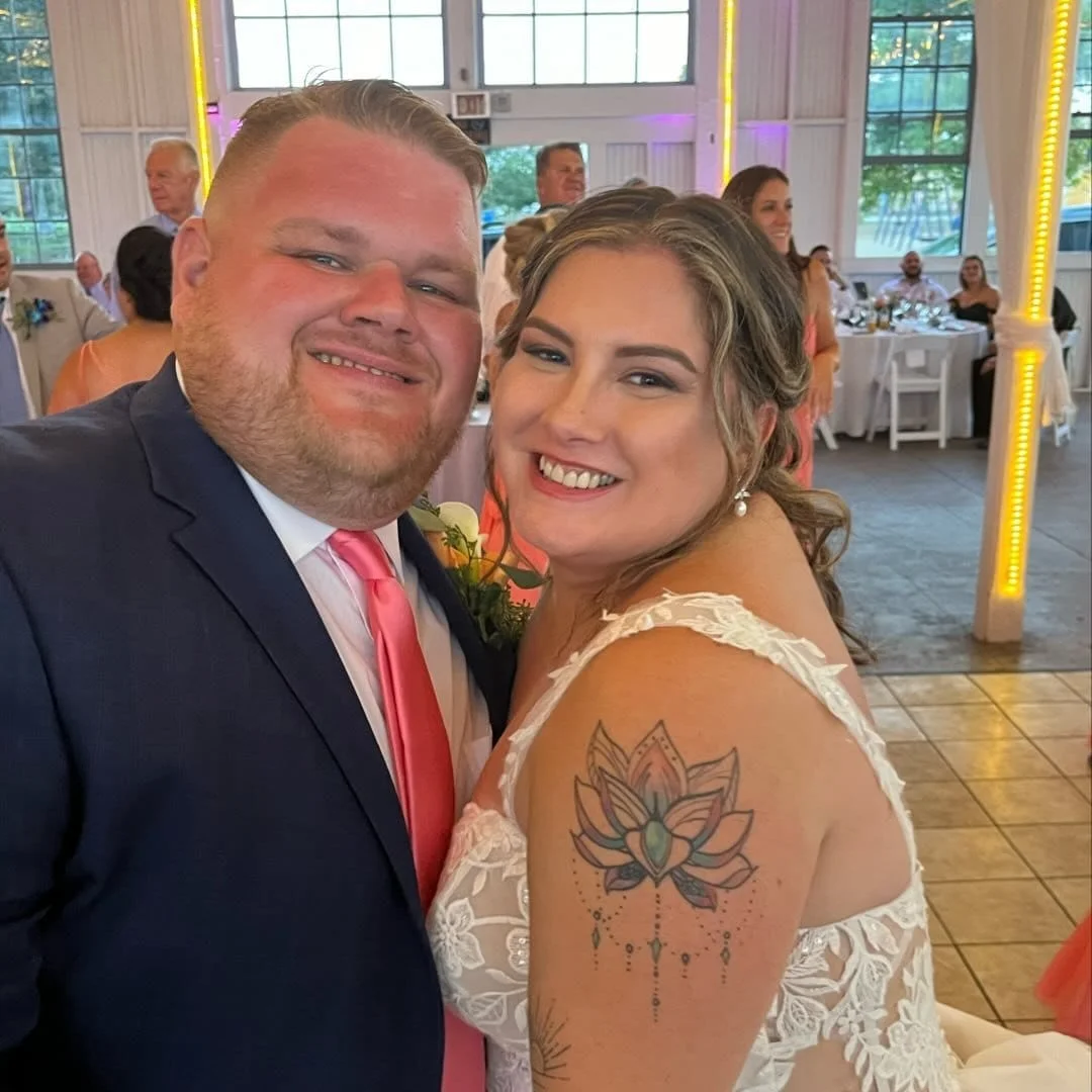 A smiling bride and groom posing close together at their wedding reception