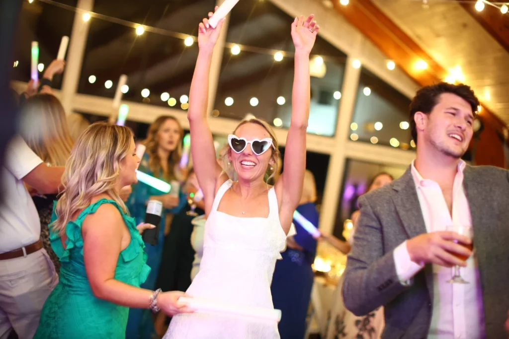 A bride in sunglasses dancing with guests on the dance floor