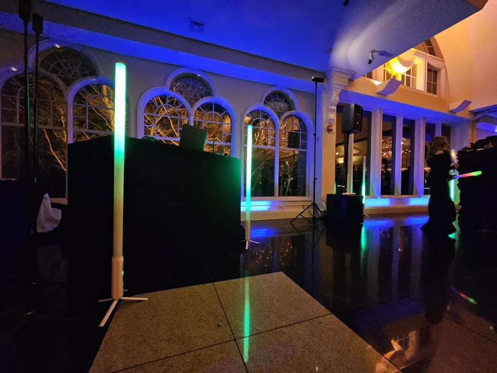 DJ booth, speakers and colored uplighting set up in a ballroom before guests arrive