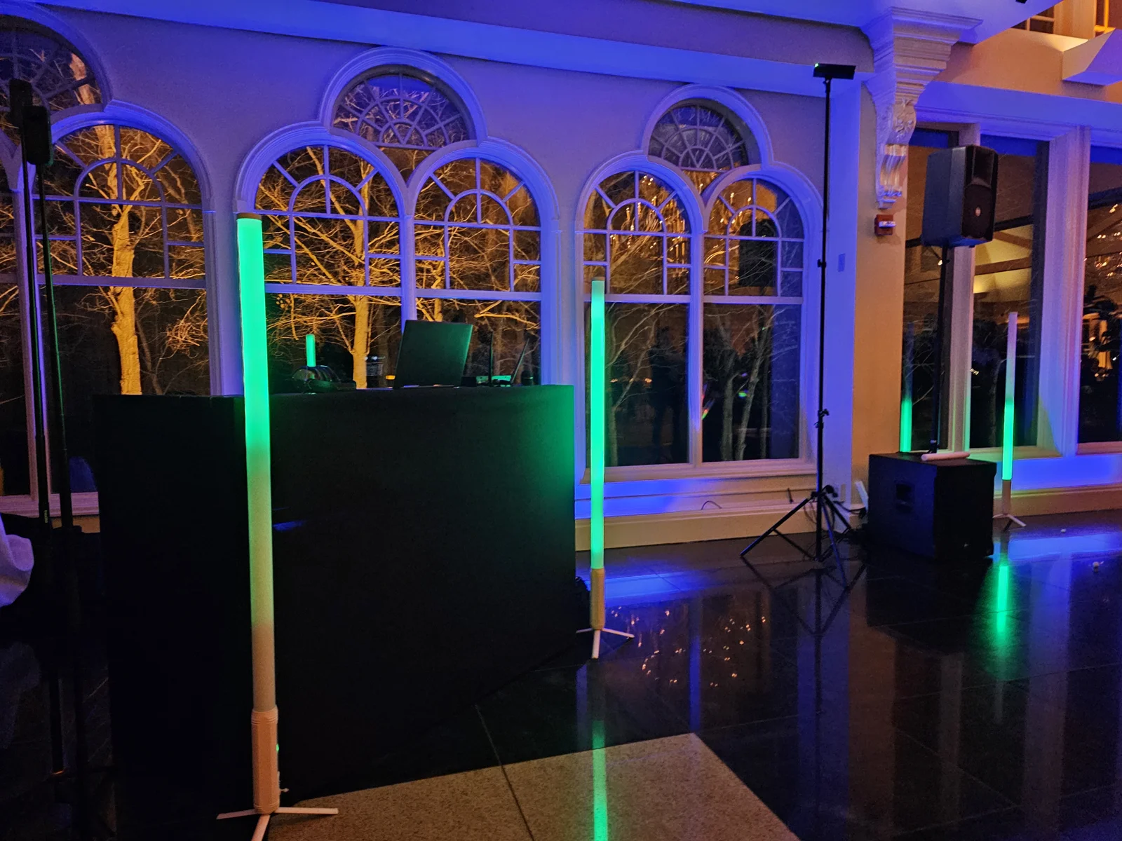 DJ booth with colored uplighting in an empty ballroom with arched windows