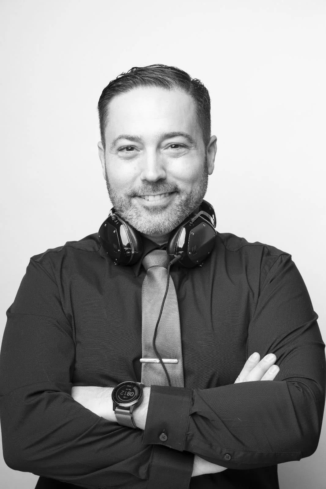 Black and white portrait of Michael Sage, Westport wedding DJ and MC, arms crossed with headphones around his neck