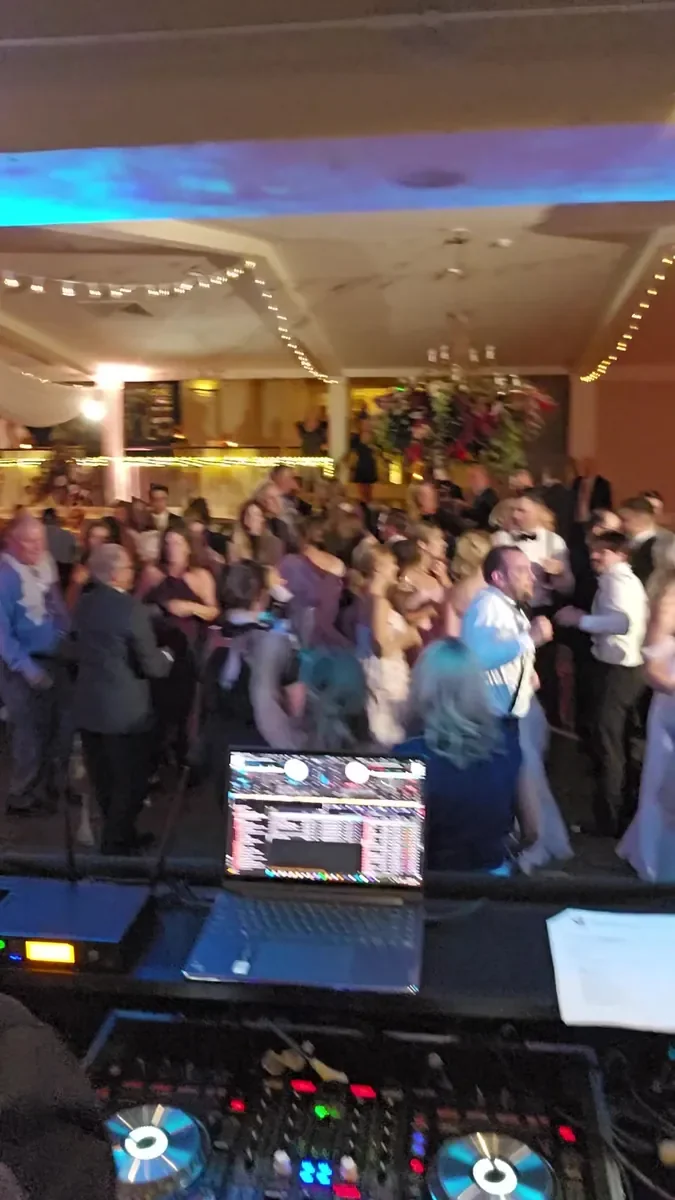 A packed dance floor seen from behind the DJ controller