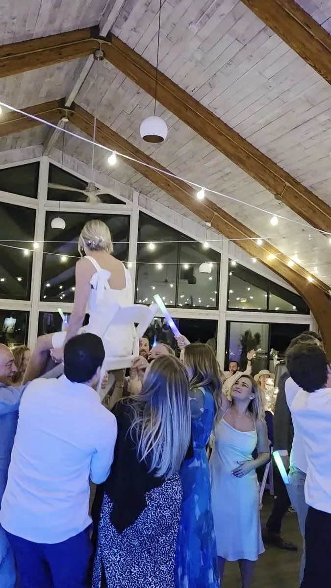 Guests gathered around as the bride is lifted in a chair during the hora